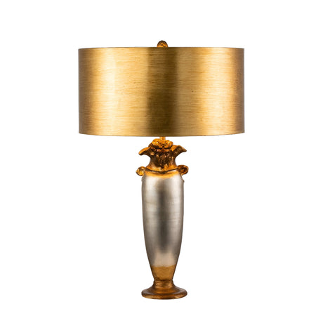The Bienville 1 Light Table Lamp in Silver/Gold and Brown features a metallic body with a gold and silver finish, complemented by an ornate base and a wide, cylindrical gold lampshade. This design beautifully merges modern style with classical elements to create an elegant and sophisticated look.