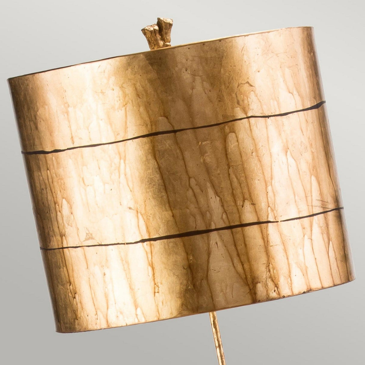 Introducing the Fragment 1 Light Floor Lamp in Aged Gold, featuring a cylindrical shade with a marbled texture and accented by three thin horizontal lines. Its partially visible base suggests a minimalist design that effortlessly provides ambient lighting.