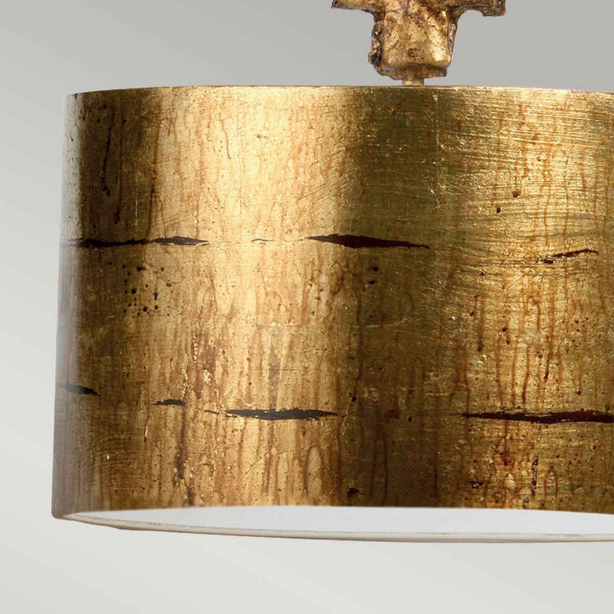 A detailed view of the Fragment 1 Light Pendant in aged gold, featuring a textured drum-shaped shade with a metallic finish. Set against a soft, neutral backdrop, the lamp's luxurious and contemporary design is beautifully highlighted.