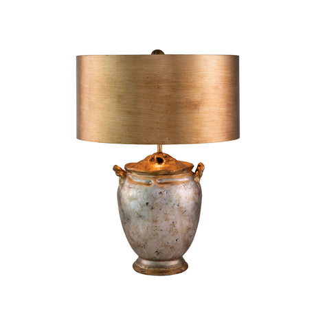 Introducing the Jackson 1 Light Table Lamp, featuring a rustic urn-shaped base crafted from aged metal and adorned with two small handles. The base boasts an antiqued silver finish, enhanced with elegant gold leaf accents to amplify its charm. Topped with a large, cylindrical beige lampshade that features a subtle texture, this lamp perfectly complements its antique-style design.