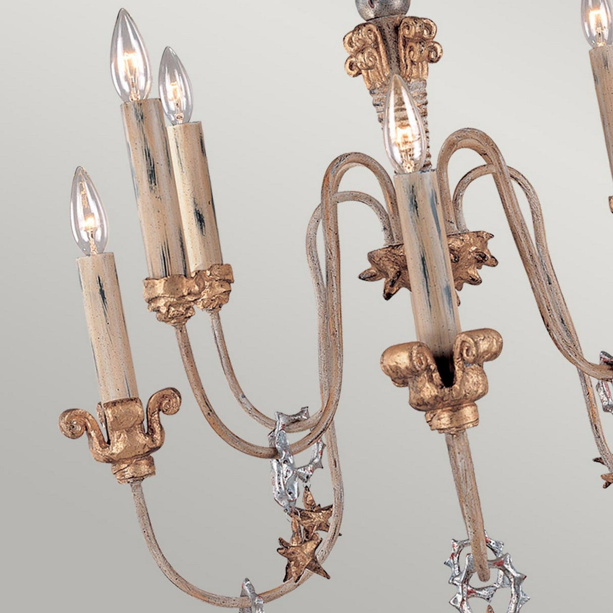 Close-up of the Mignon 8 Light Chandelier - Gold & Silver, showcasing five candle-like light bulbs. This chandelier features a distressed cream and gold leaf finish, adorned with decorative metal vines, leaves, and shimmering crystal droplets.
