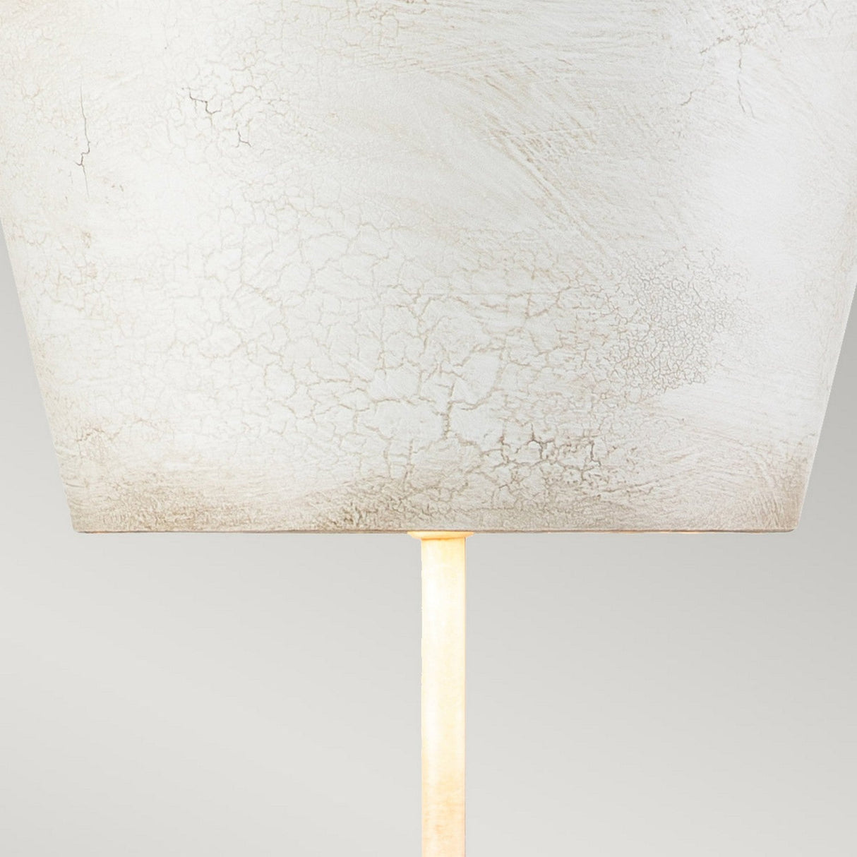 Here is a revised version of the sentence incorporating the given product data:
"Close-up of the Petra 1 Light Table Lamp - Bone White, highlighting its textured off-white shade with delicate cracks. It boasts a slender bone white base against a soft gray background, exemplifying contemporary design elegance.