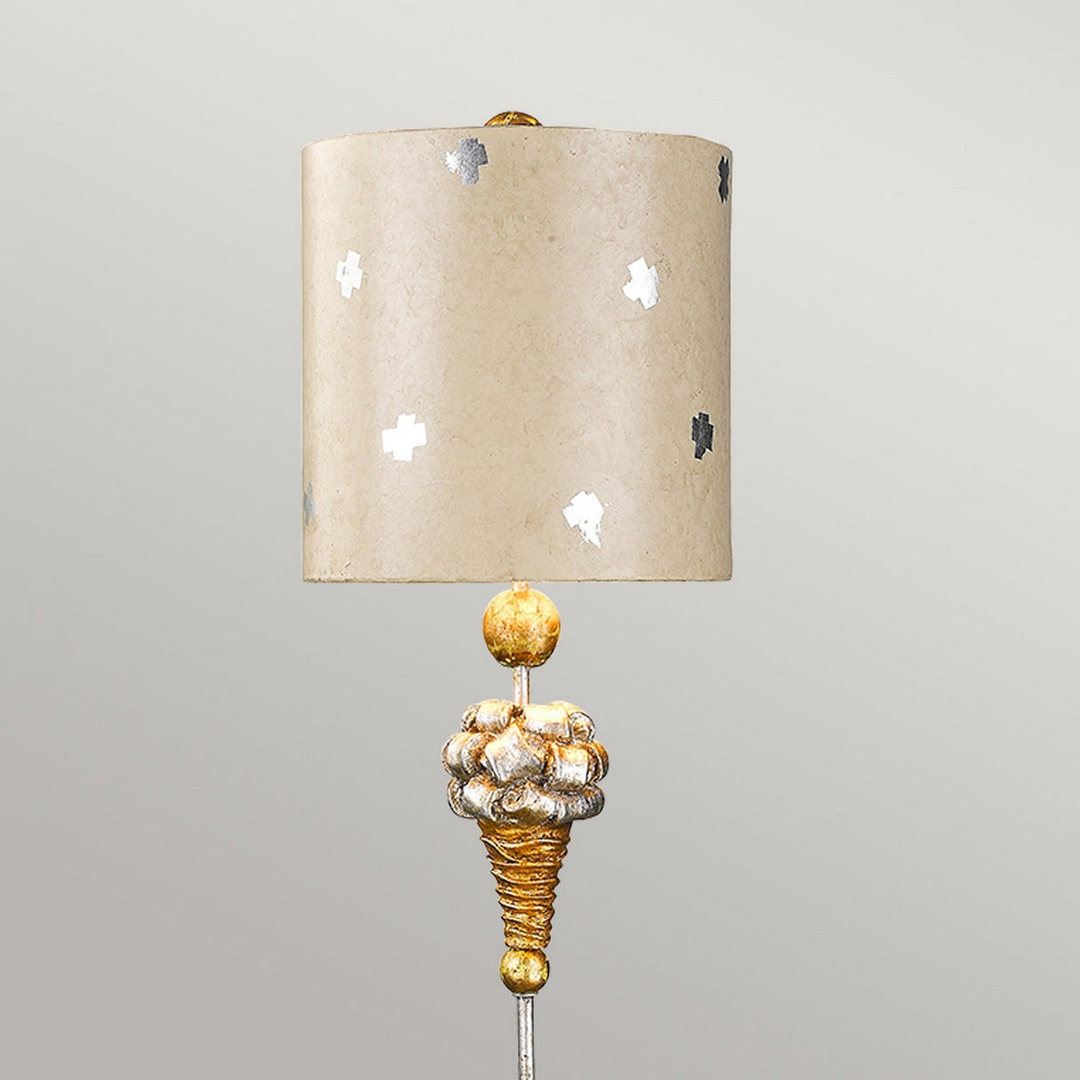 Introducing the Pompadour X 1 Light Table Lamp, featuring a cream cylindrical shade adorned with silver patterns. The base is designed to mimic the look of silver leaf, showcasing a gold and silver spiral design and topped with a finial inspired by pompadour-style elegance. It is set against a simple light gray background.