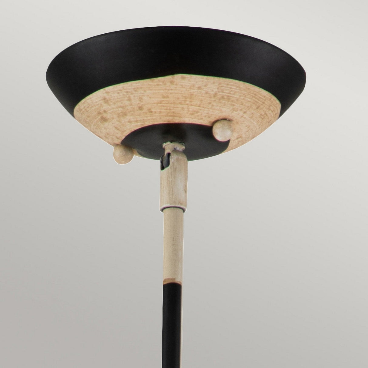 A close-up of the South Beach 1 Light Pendant showcases its black, putty, and gold leaf finish with a wide, shallow bowl design perched atop a sleek pole. Its simple, modern aesthetic exudes coastal elegance against the plain gray background.