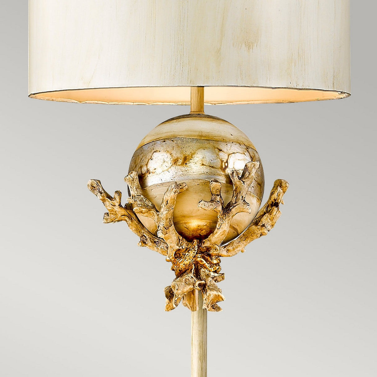 Introducing the Trellis 1 Light Floor Lamp in Putty Patina & Silver Leaf, featuring a cream lampshade perfect for enhancing your home's aesthetic. The base boasts a gold spherical design encased in an ornate branch-like structure with exquisite hand-painted details, set against a plain light gray background that highlights its elegance.