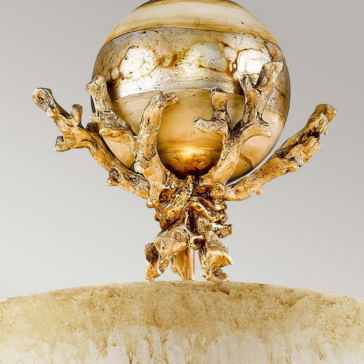 The Trellis 1 Light Pendant - Putty Patina & Silver Leaf showcases a polished silver leaf orb element supported by intricately designed branches that resemble organic coral formations. These branches, hand-painted with a putty patina finish, are set atop a textured cream-colored base against a gray background.