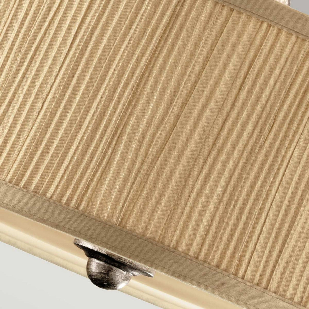 Close-up of a hanging light fixture featuring the Abbey 3 Light Semi Flush design, showcasing a textured beige fabric shade with vertically pleated sophistication and a metallic accent at the bottom. The elegant Silver Sand finish enhances its refined appearance.