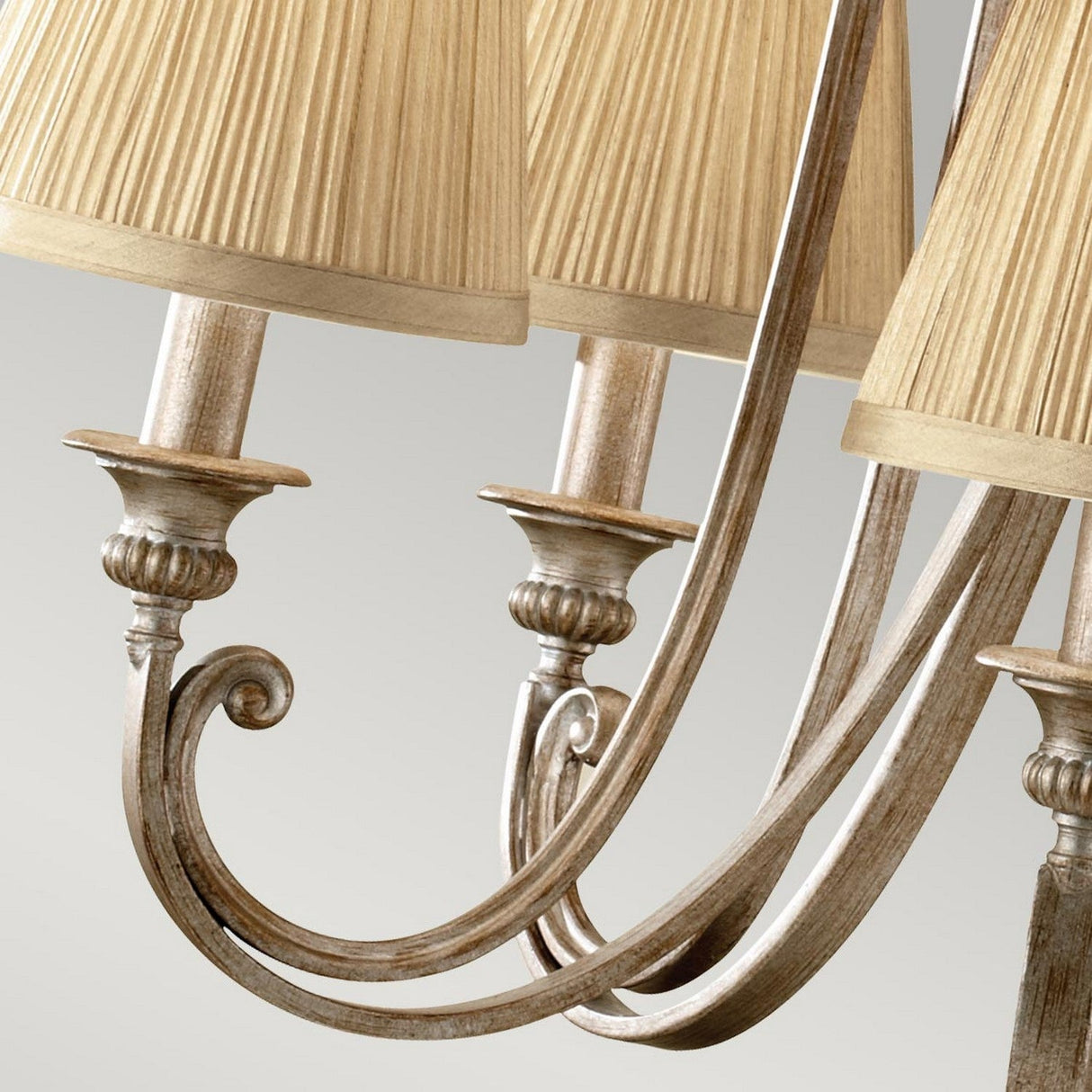 A close-up of the Abbey 5 Light Chandelier - Silver Sand highlights its curved metal arms and gold, fluted fabric lampshades, offering an elegant and vintage aesthetic against a neutral backdrop.