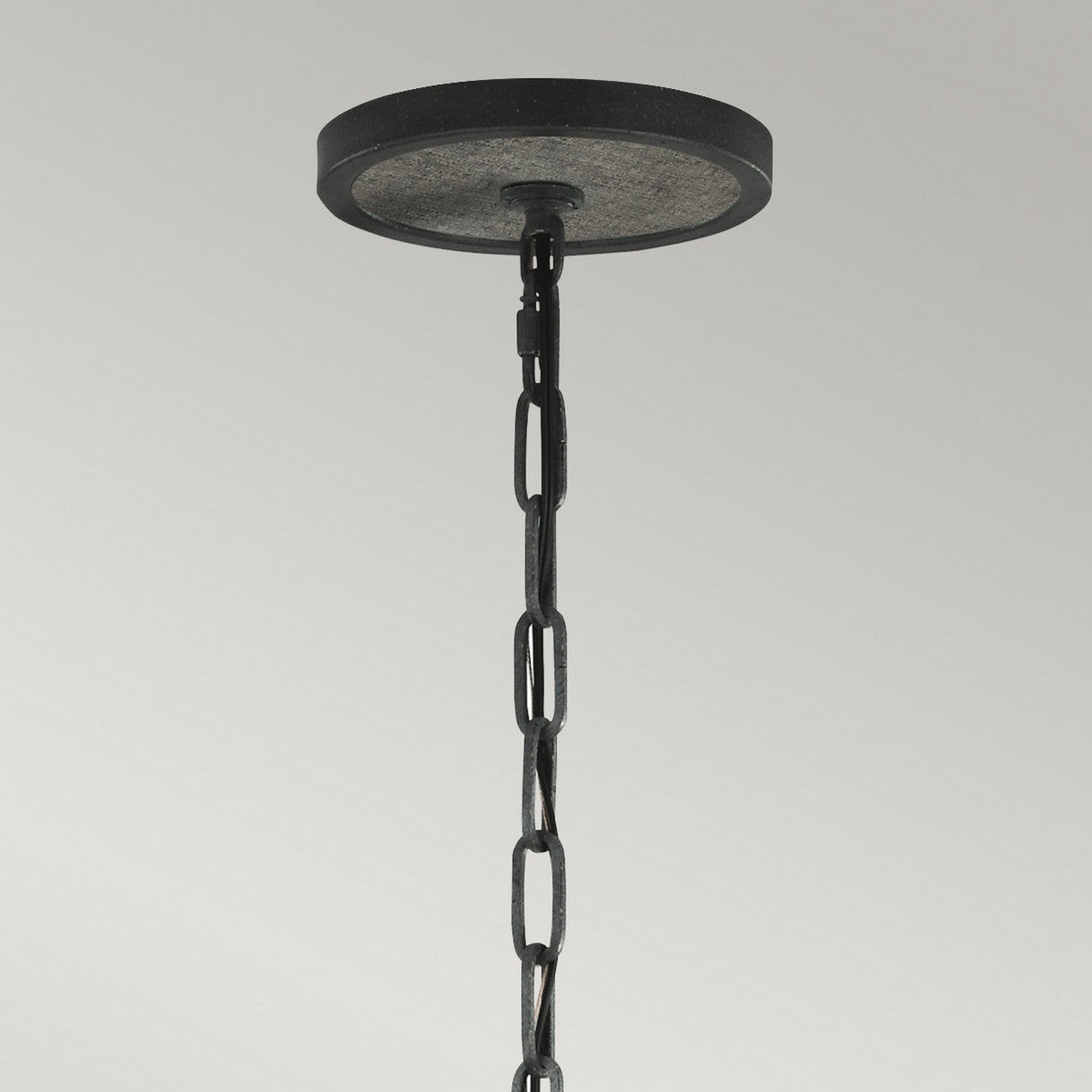 A close-up of a chain from the Allier 4 Light Chandelier, featuring weathered oak wood and antique forged iron, hangs from a circular ceiling mount against a plain gray background, capturing the rugged charm of rustic industrial lighting.