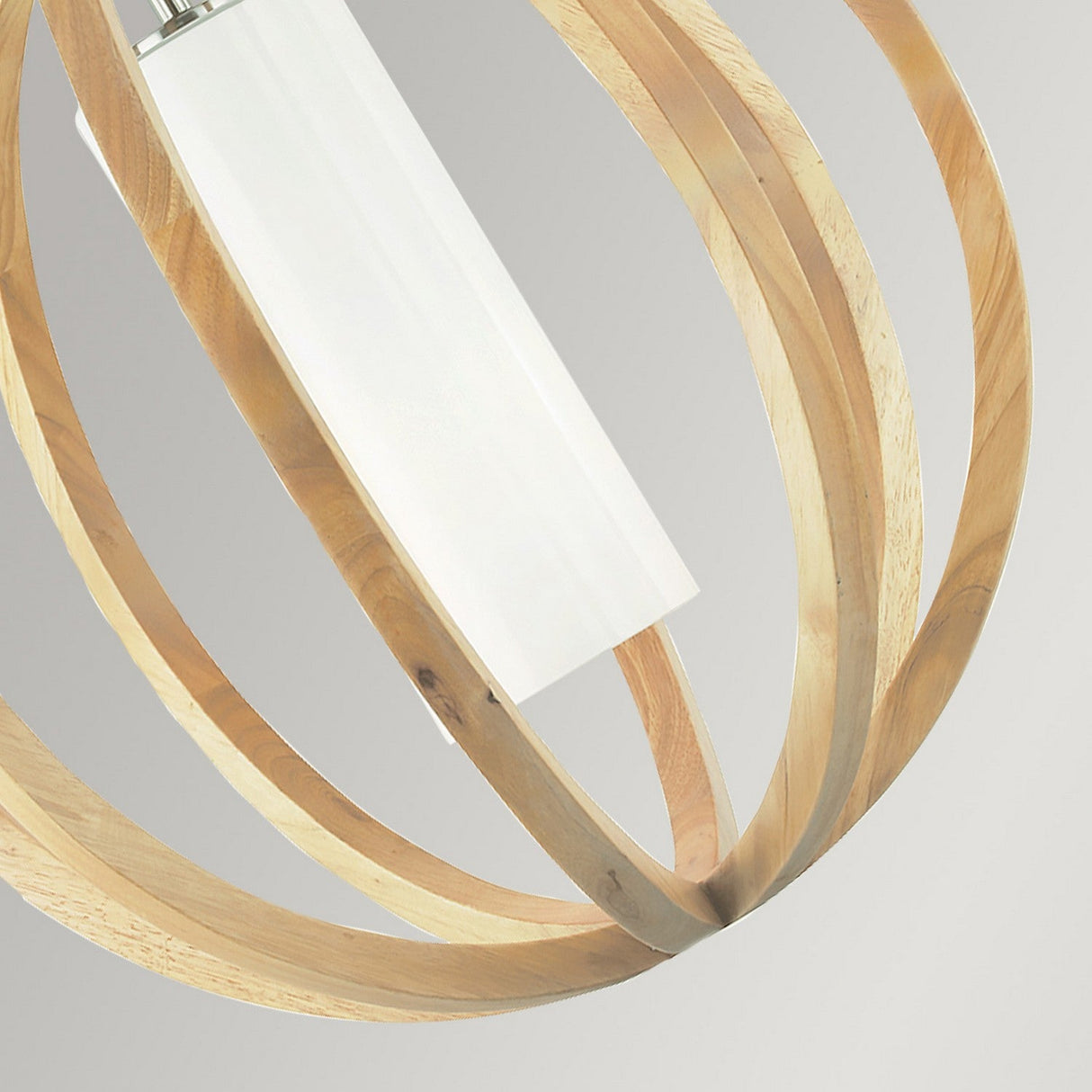 Close-up of the Allier 1 Light Small Pendant in light wood and brushed steel, showcasing a white cylindrical bulb surrounded by a spherical wooden frame made of curved strips. The neutral gray background accentuates the modern rustic aesthetic of this stylish lighting fixture.