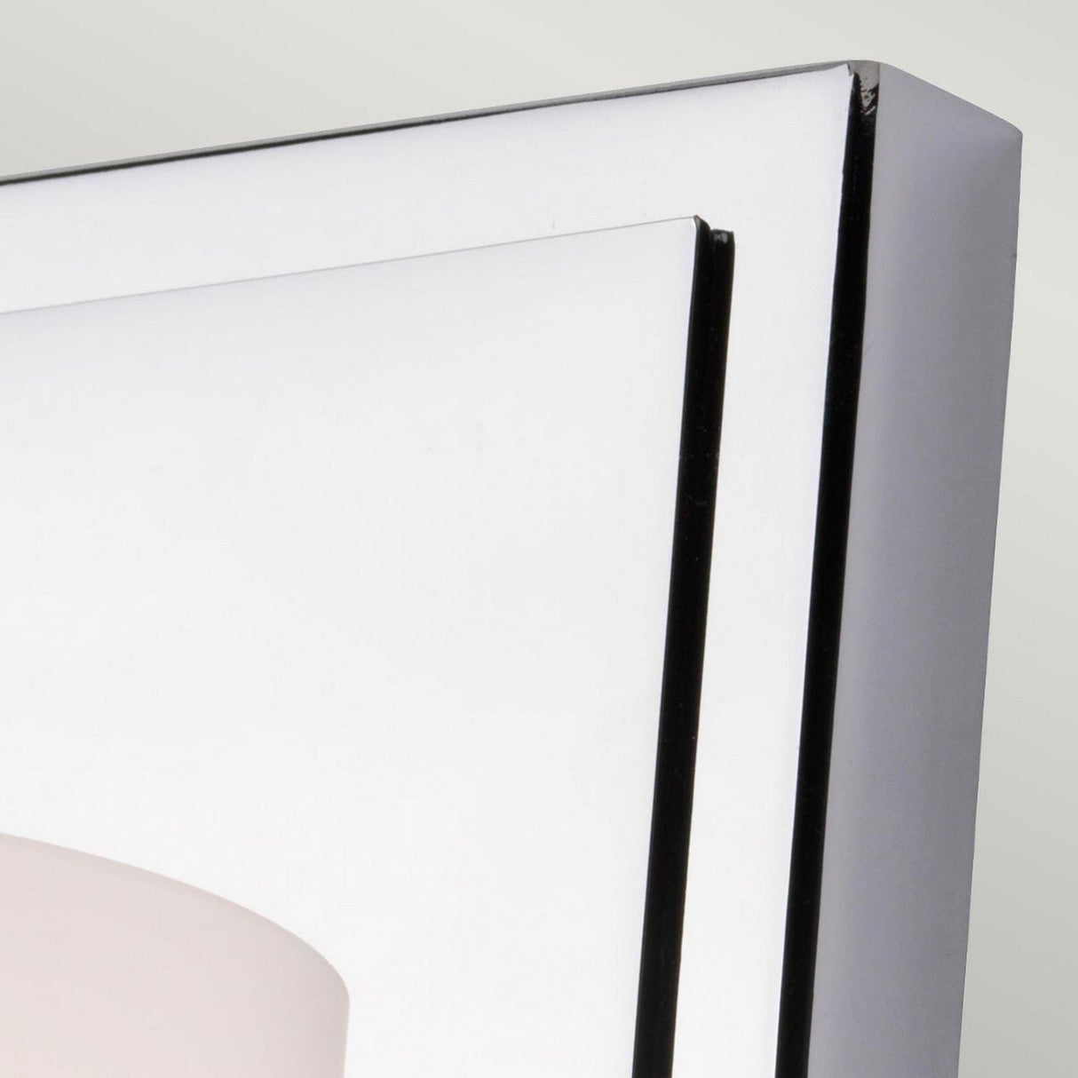 Detailed view of the Amalia 1 Light Large Wall Light - Polished Chrome showcasing a sleek, angular frame. Its geometric design with overlapping layers and smooth surfaces brings a modern touch, harmonizing seamlessly with its IP44 rating for both style and durability against a light background.