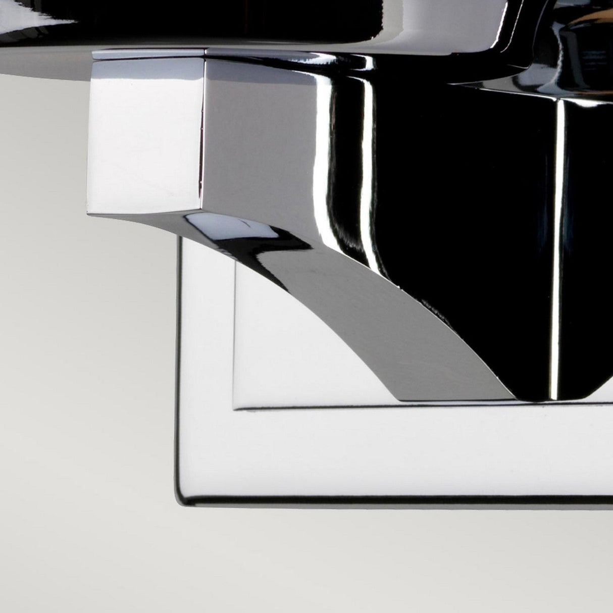 Close-up view of a modern, metallic chrome faucet against a light gray background. The design features sleek, angular lines with smooth reflective surfaces, akin to the elegance of the Amalia 1 Light Small Wall Light in polished chrome.