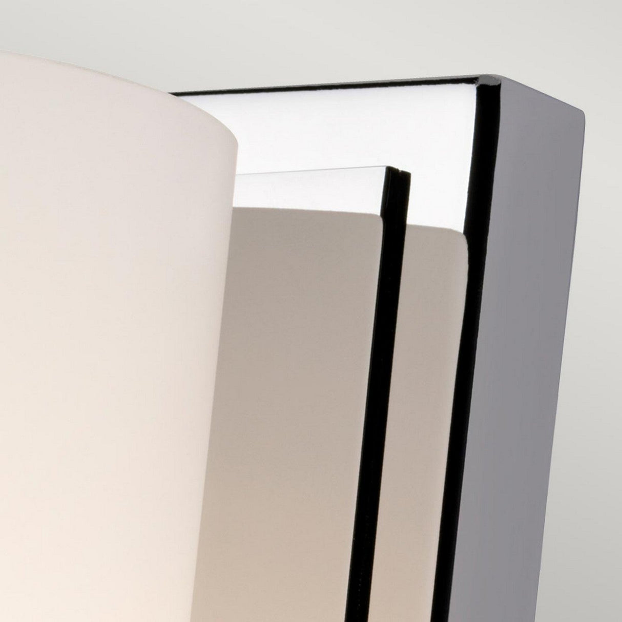 Close-up of the Amalia 1 Light Small Wall Light in a sleek black and white design. This bathroom lighting fixture features a curved white opal etched glass shade and is available with either a polished chrome or black metal backplate, set against a light gray background.