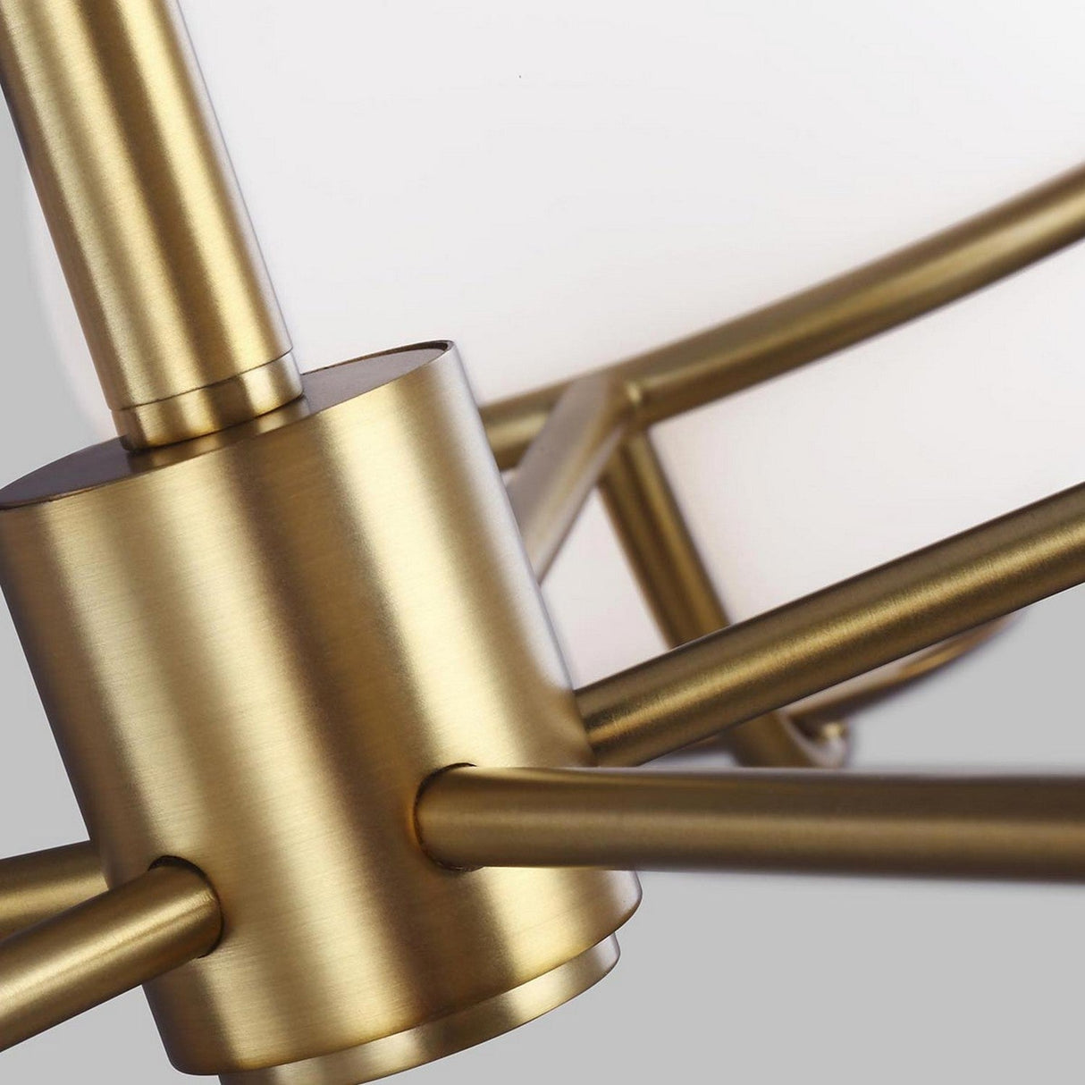 Close-up of the Apollo 5 Light Chandelier - Burnished Brass, a modern marvel in burnished brass. Its sleek metallic design with multiple rods extends from a central cylindrical hub, creating an abstract geometric pattern. The fixture is adorned with white opal etched glass against a neutral backdrop.