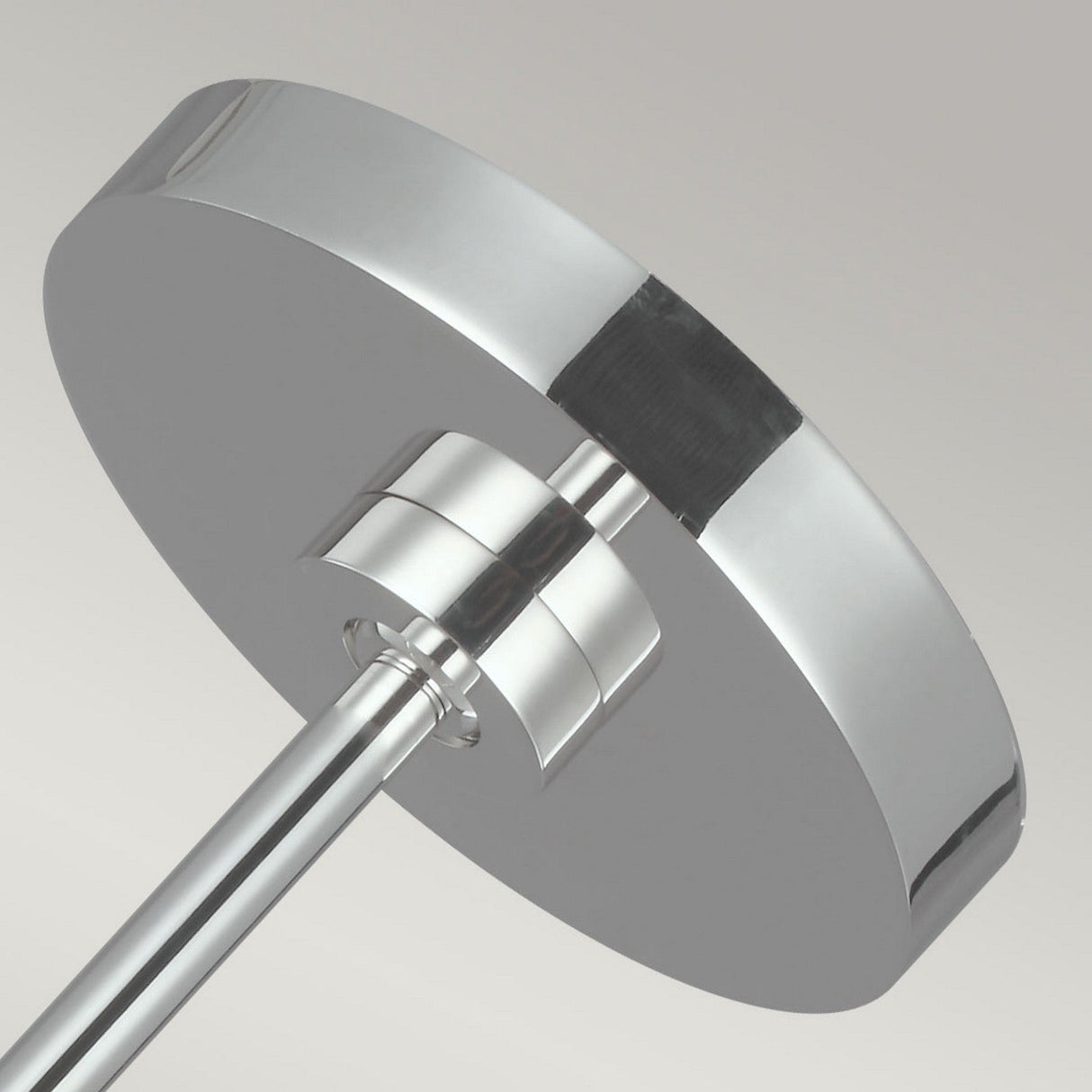 Close-up of a contemporary chrome fixture with a circular, flat, reflective surface and elegant stem in polished nickel, set against a neutral gray backdrop.
