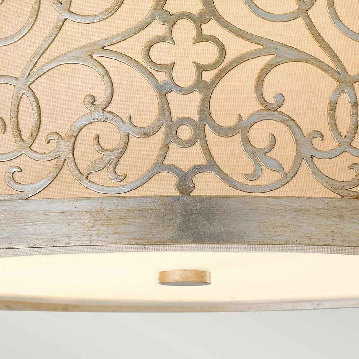 Detailed view of the Arabesque 2 Light Flush - Silver Leaf Patina, showcasing its intricate laser-cut scrollwork and swirling patterns with a floral motif on a beige background. The bottom of the fixture is elegantly finished with a Silver Leaf Patina ring.