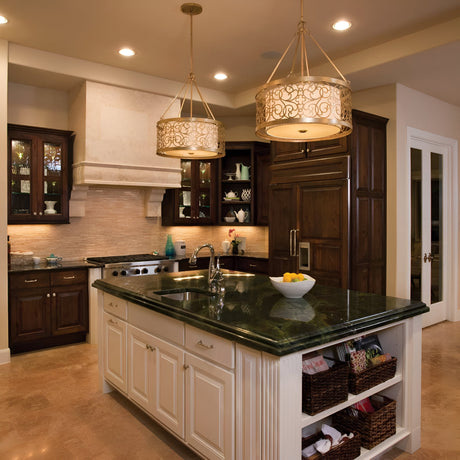 A contemporary kitchen boasts a central island with a green marble countertop, complete with a sink, storage shelves, and a bowl of lemons. Dark wood cabinets provide rich contrast while the Arabesque 4 Light Chandelier in Silver Leaf Patina adds an elegant illumination to the space. Stainless steel appliances finish off the sophisticated design aesthetic.