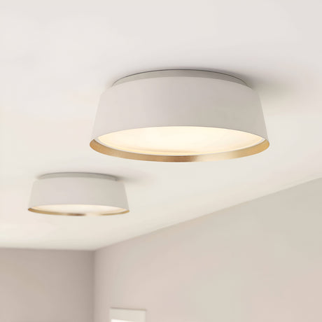 Two Asher 3 Light Flush fixtures, featuring a matte white finish with gold interior edges, are installed on a minimalist white ceiling. These contemporary lights gently illuminate the space, creating a warm ambiance that perfectly complements minimalist interiors.