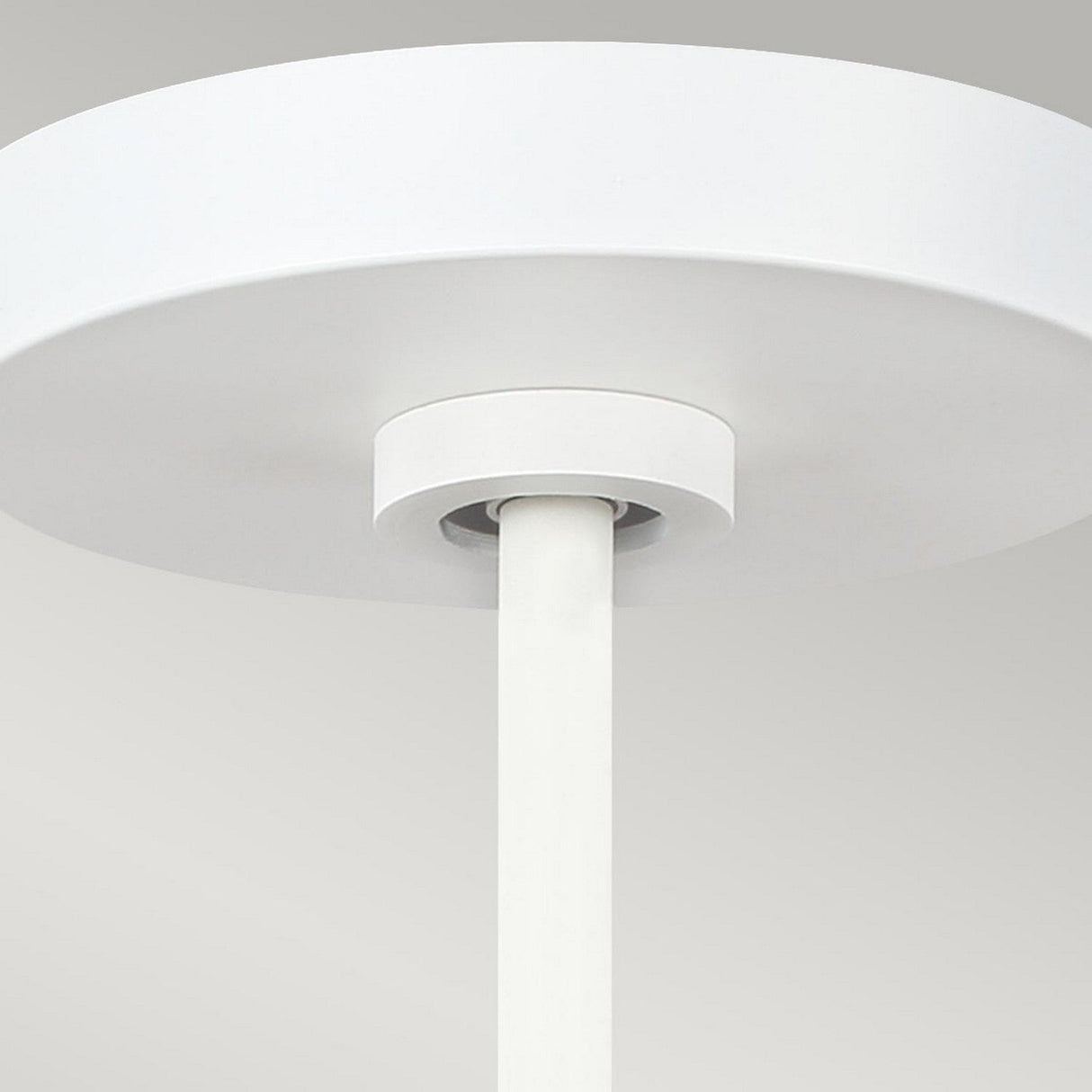 A close-up of the Asher 5 Light Pendant in Matte White & Gold showcases its minimalistic ceiling-mounted design featuring a cylindrical stem and circular base, elegantly highlighted against a light gray background.