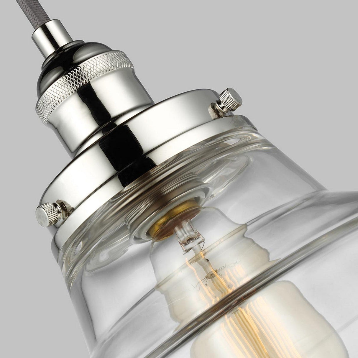 Close-up of the Baskin-1 1 Light Pendant in polished nickel, featuring a sleek and contemporary design with a clear glass shade set against a gray background. The visible bulb accentuates the fixture's elegant metallic finish.