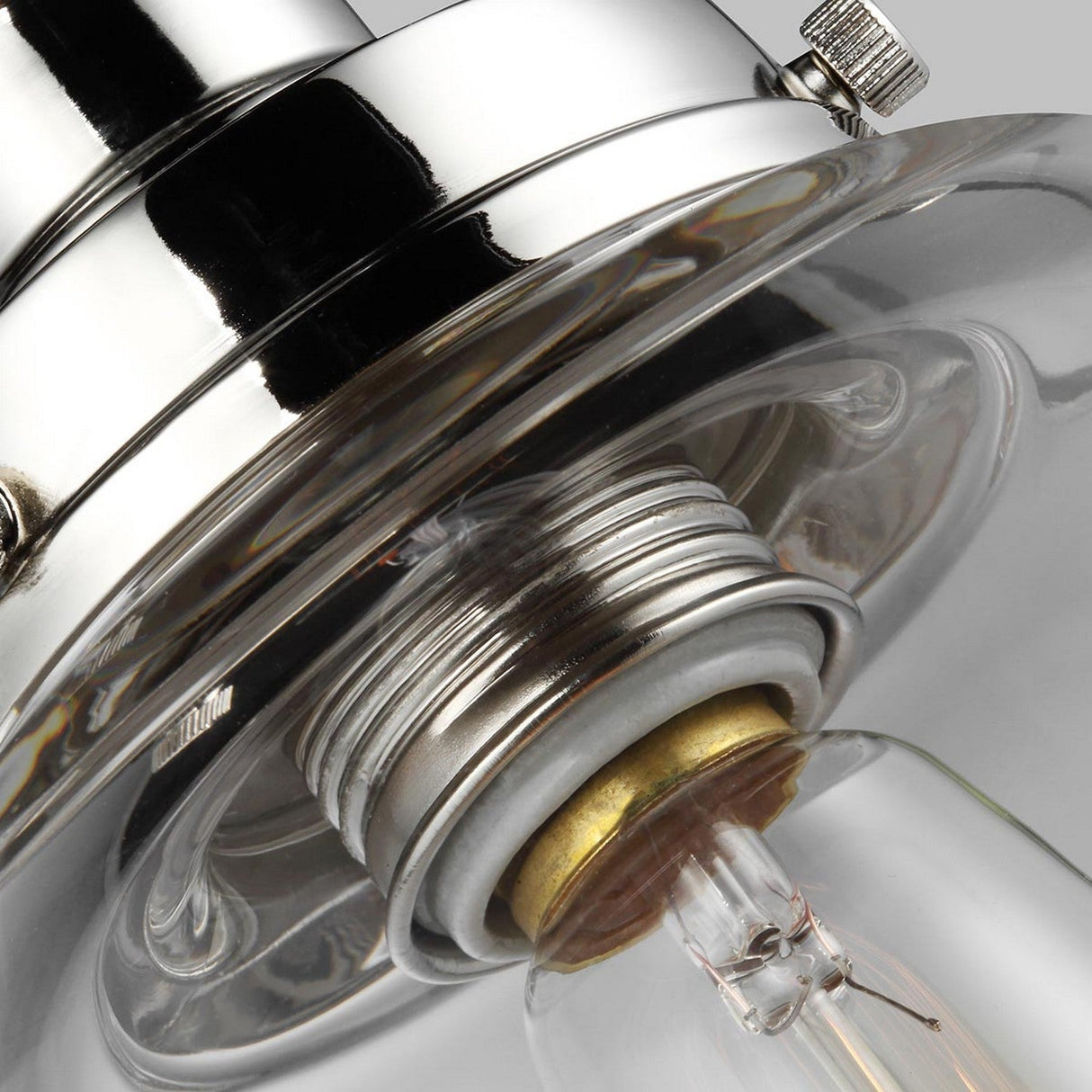 The image offers a close-up view of the Baskin-2 1 Light Pendant in Polished Nickel, showcasing a partially screwed-in clear glass bulb. The socket's shiny, polished nickel finish reflects light, accentuating its modern aesthetic. The focus on the connection between the bulb and socket highlights its detailed design.