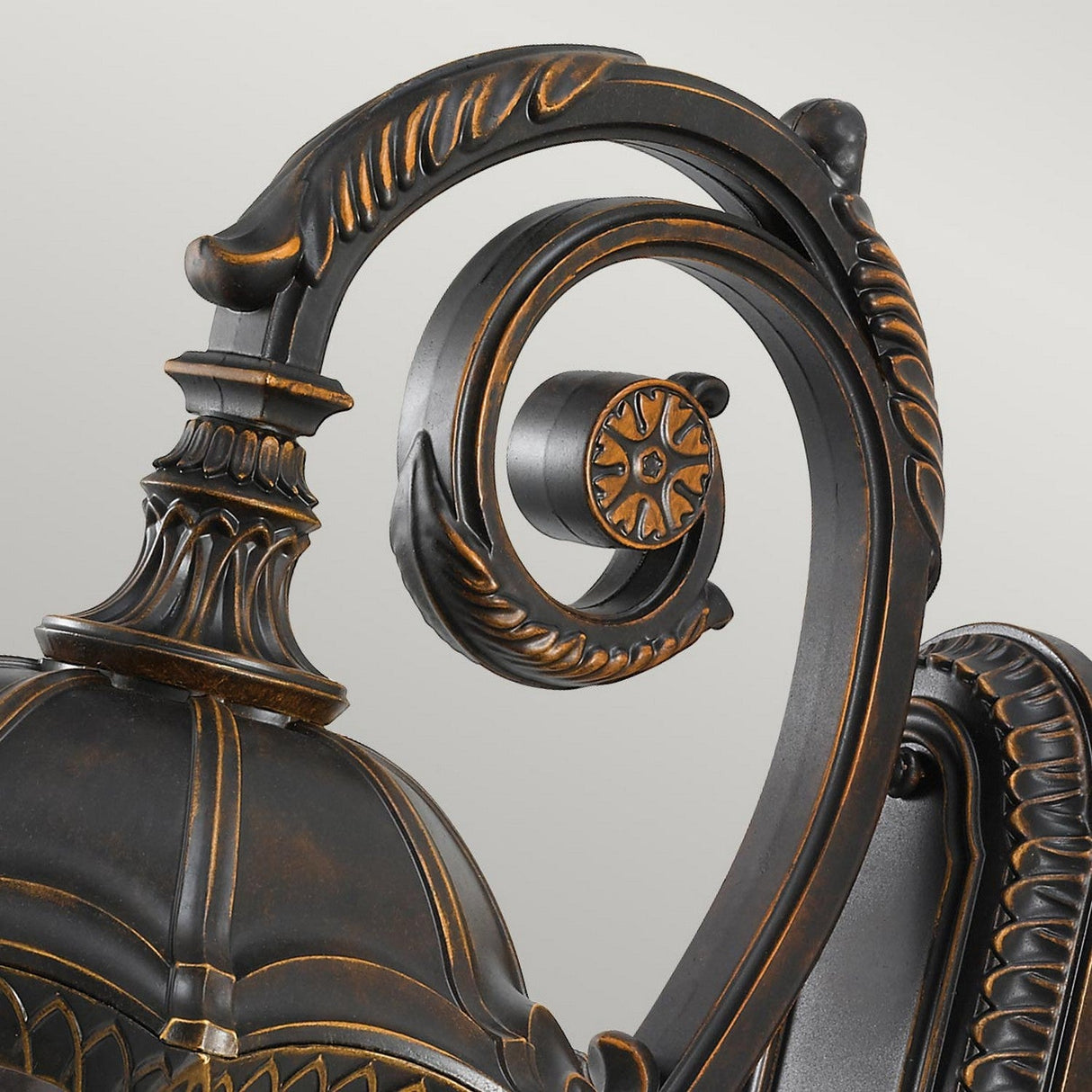 Close-up of an ornate, vintage-style metal lamp post featuring swirling decorative scrolling and intricate detailing. The elegant walnut finish, reminiscent of classic outdoor lighting, mirrors the sophisticated design found in the Baton Rouge 4 Light Outdoor Large Wall Lantern.