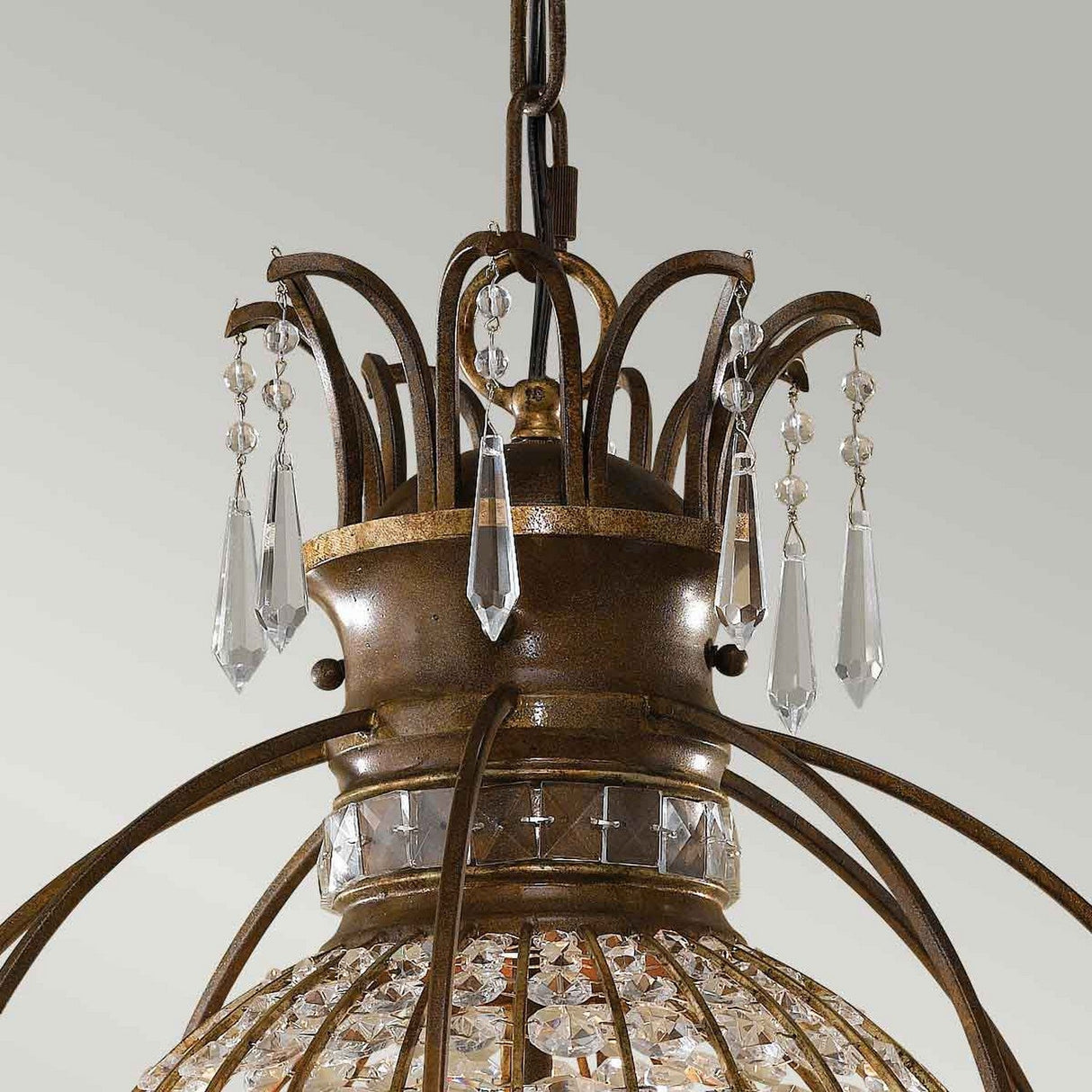 Experience the elegance of the Bellini 3 Light Chandelier in Oxidized Bronze/British Bronze, featuring intricate metalwork with gracefully curved arms, sparkling antique quartz crystal details, and hanging crystal pendants set against a light backdrop.