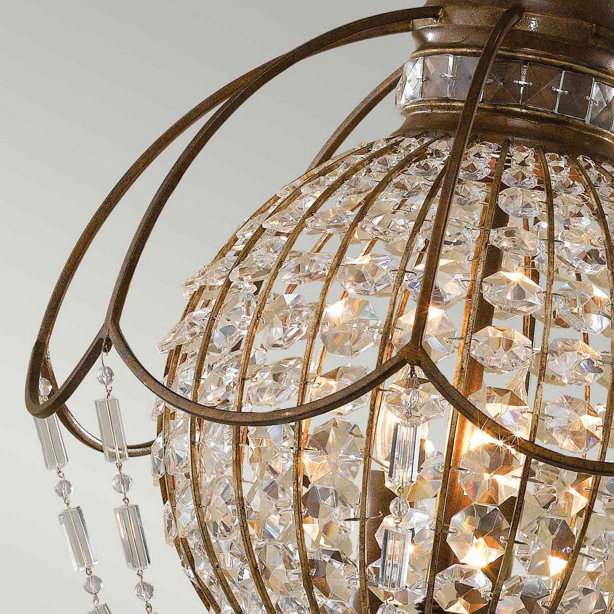 Here's a revised version of the sentence using the provided product data:
A close-up of the Bellini 3 Light Chandelier in Oxidized Bronze/British Bronze showcases its spherical frame, intricately adorned with numerous antique quartz crystals. The metal structure is elegantly curved into a cage-like design, complete with hanging crystal pendants that beautifully reflect and refract light.