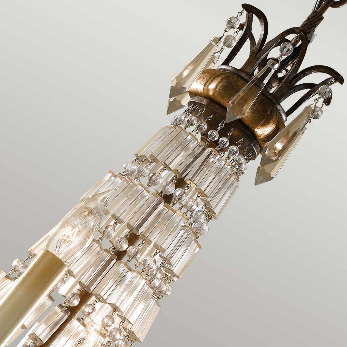A close-up of the Bellini 4 Light Chandelier in Oxidized Bronze/British Bronze highlights its crystal prisms and beads, with the top displaying detailed metalwork. The antique quartz crystals beautifully reflect light, casting an elegant and dazzling effect against a neutral backdrop.