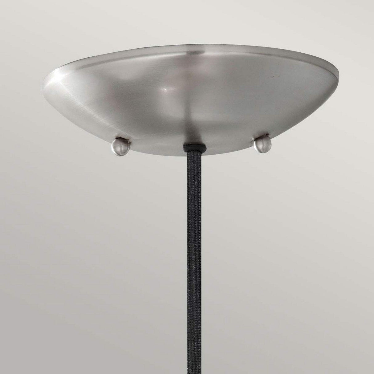 The Beso 1 Light Medium Pendant - Brushed Steel showcases a brushed metal ceiling fixture with a sleek, dome-shaped canopy and a textured black cord. Highlighted by its two visible screws on the canopy and set against a light gray background, it perfectly captures classic retro lighting with a minimalist charm.