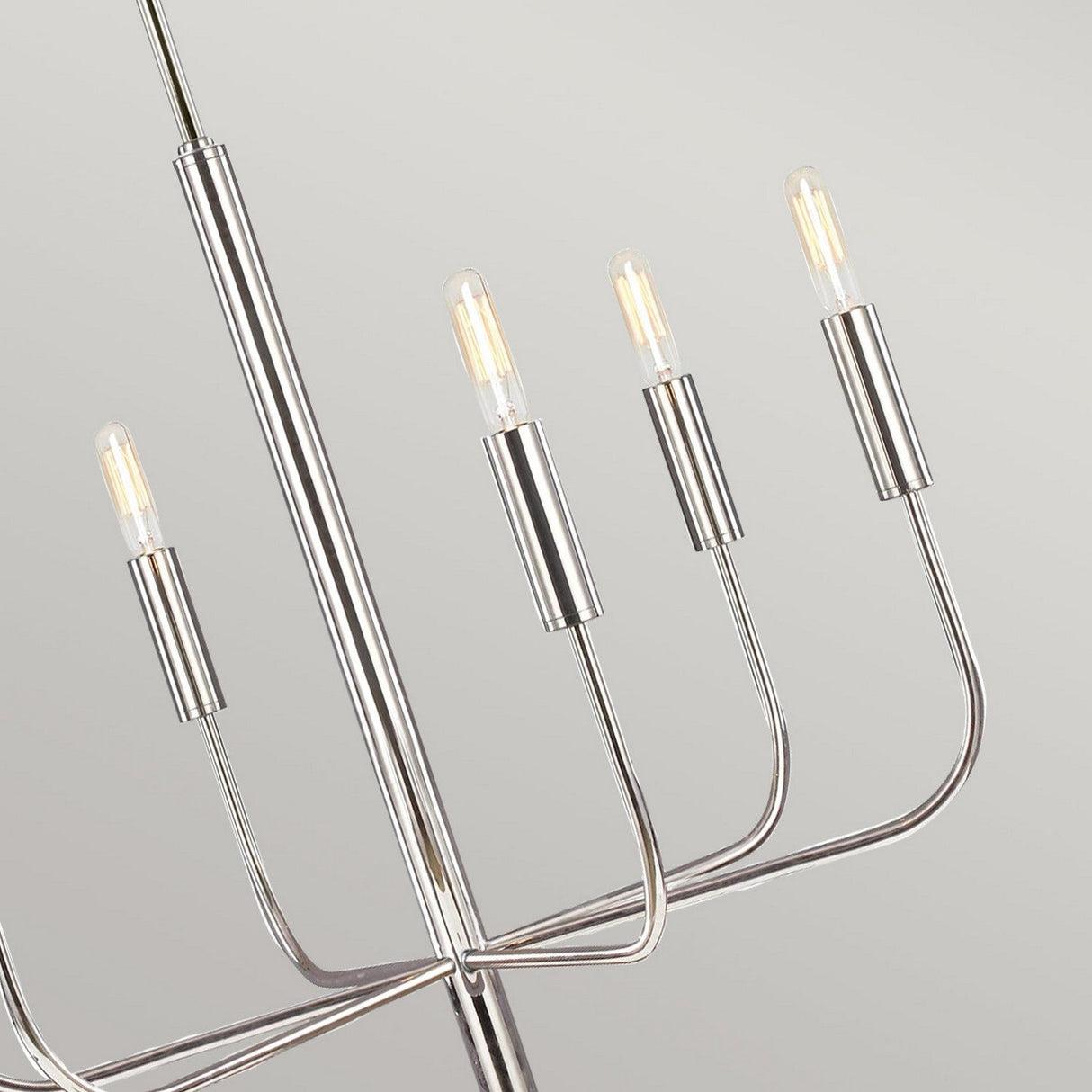 The Brianna 6 Light Chandelier in polished nickel features a sleek metallic design with six upward-facing bulb holders, each supporting a slender bulb. Its lustrous finish gleams brilliantly, casting an elegant glow that enhances any neutral backdrop with its contemporary charm.