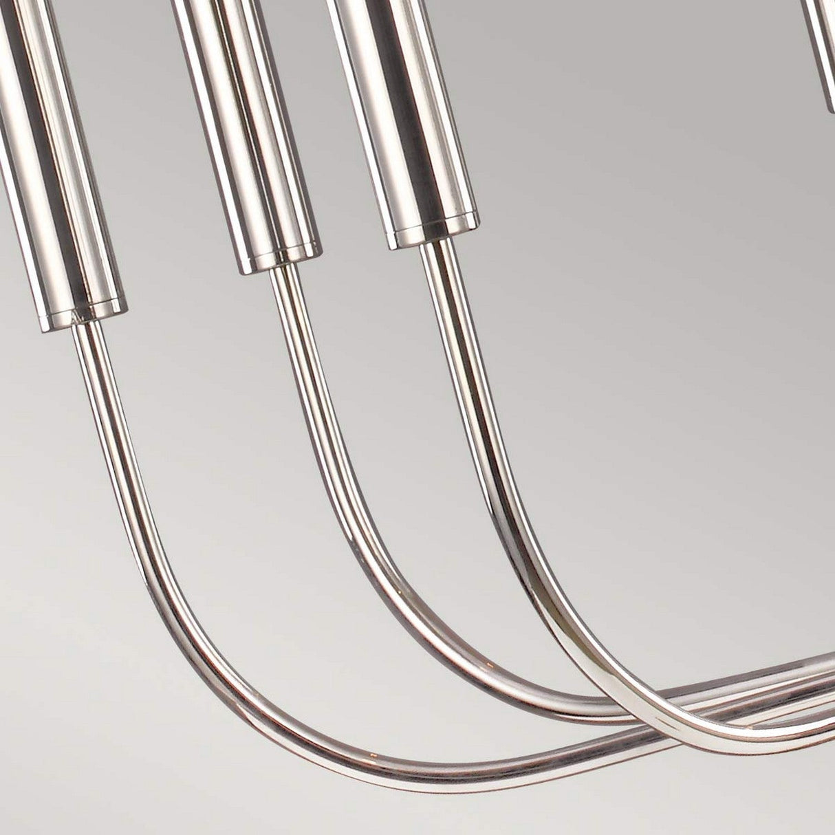 The Brianna 9 Light Chandelier - Polished Nickel exemplifies modern luxury lighting with its polished nickel finish, featuring sleek, curved cylindrical arms set against a neutral backdrop.