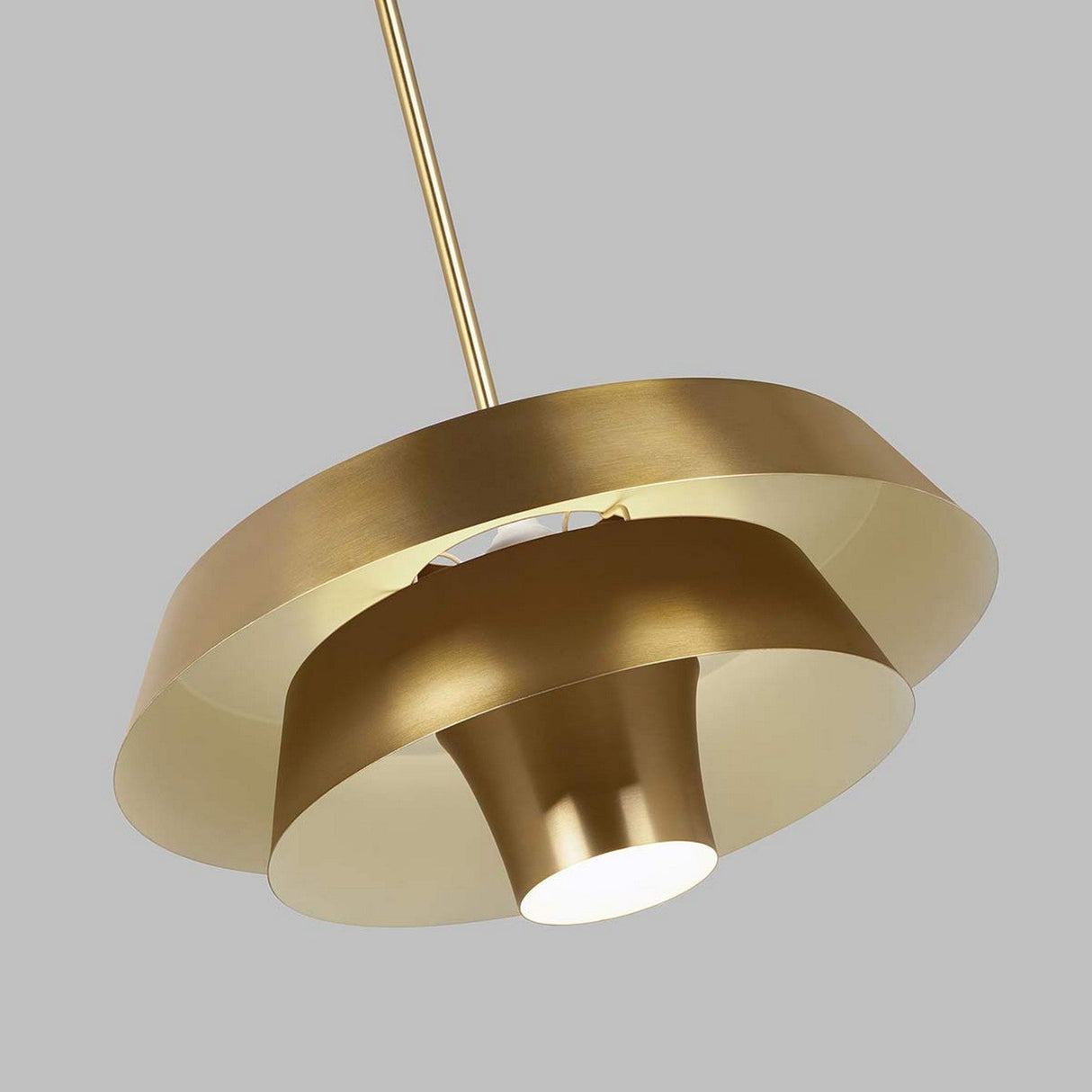 The Brisbin 1 Light Pendant features a contemporary design with a sleek burnished brass finish, highlighting its Mid-Century style through an outer circular ring and an inverted conical center. This fixture provides ambient lighting while hanging gracefully from a rod against a plain gray backdrop.