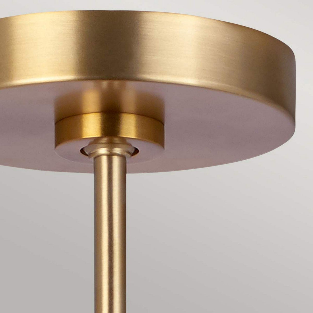 A close-up of the Brisbin 1 Light Pendant in burnished brass features a round base and cylindrical stem, capturing a sleek Mid-Century design. The neutral background enhances its modern aesthetic, making it ideal for ambient lighting.