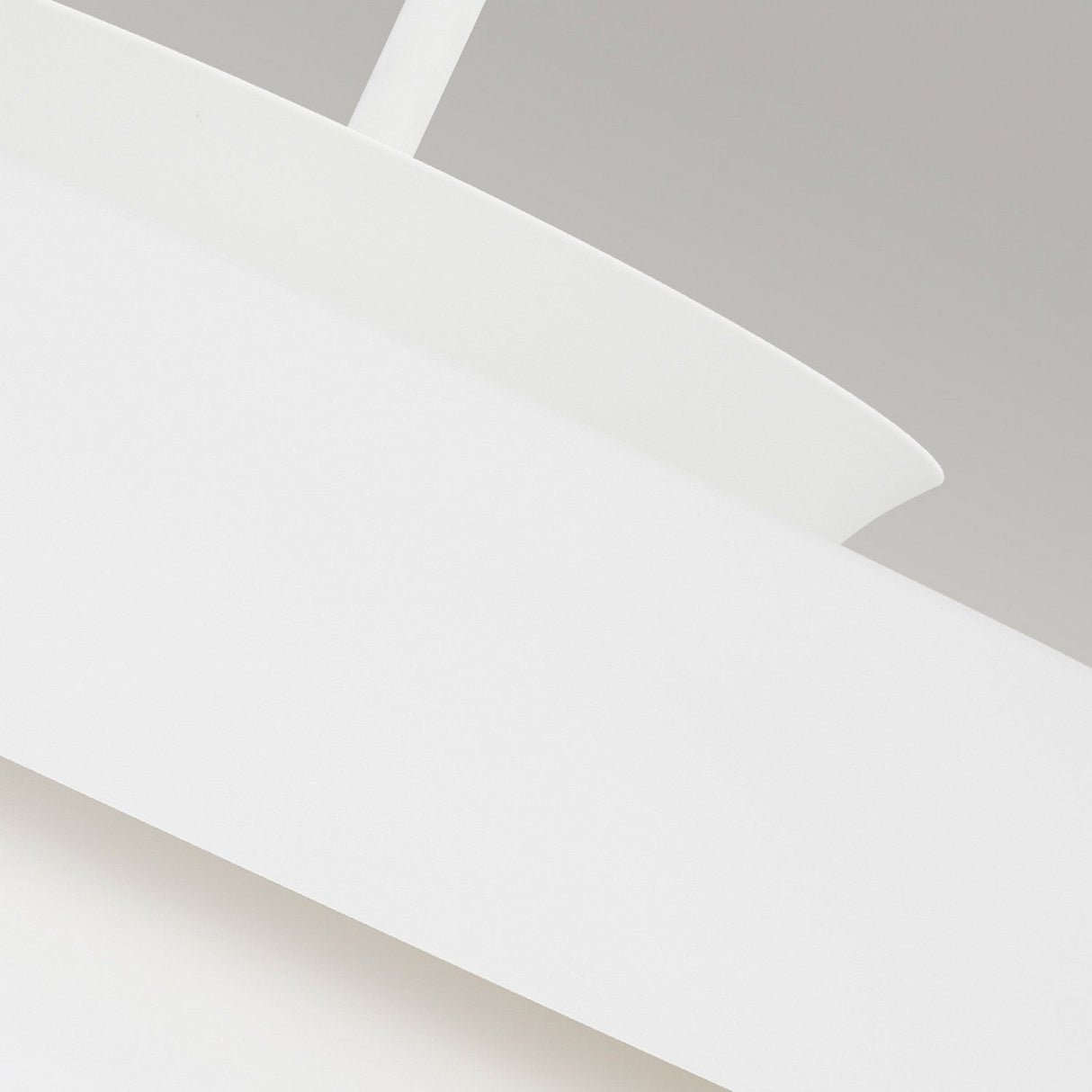 Close-up of the Brisbin 1 Light Pendant in matte white against a neutral background. This lamp boasts smooth, curved surfaces and a cylindrical shape, emanating an ambient glow that accentuates its modern, mid-century design.