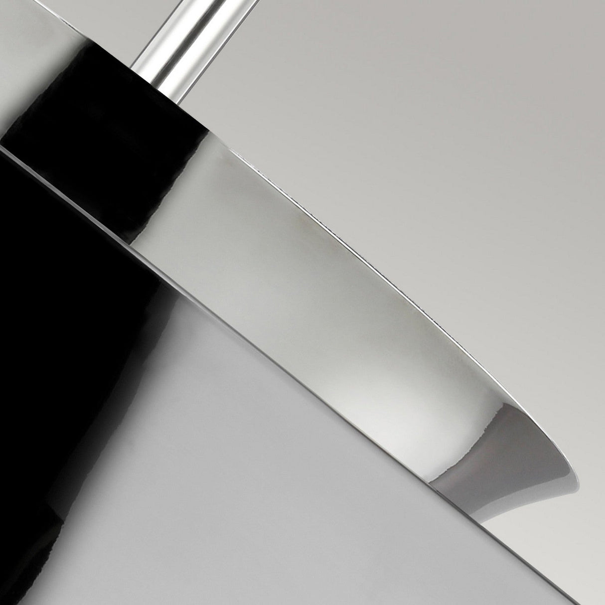 A detailed view of the Brisbin 1 Light Pendant - Polished Nickel, showcasing its smooth, reflective surface and elegantly curved edge. The lustrous metal exemplifies mid-century modern design with contrasting highlights and shadows set against a neutral backdrop.