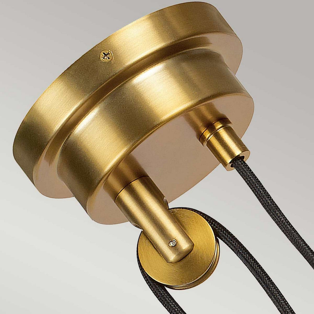 Close-up of the Candor 1 Light Pendant in matte white and brass, exuding a modern vintage lighting vibe. This adjustable pendant light features two black cords connected to its circular base, highlighting a sleek metallic finish against a plain background.