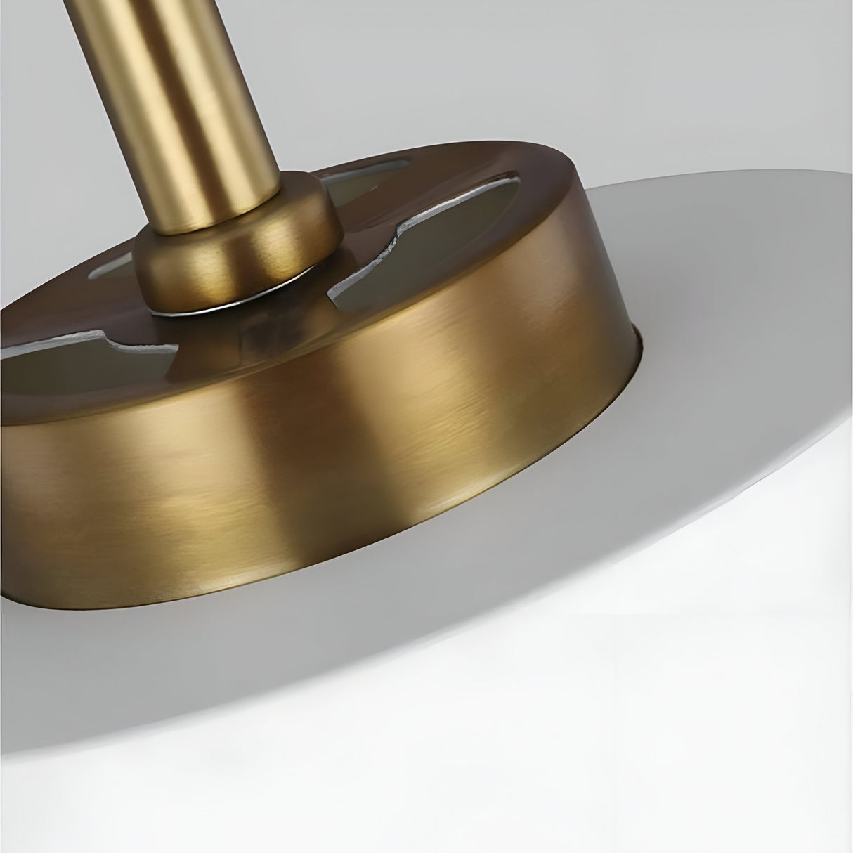 Close-up of the Carter 1 Light Pendant in matte white with brass accents, showcasing the base and part of the shade. The fixture, suspended from the ceiling, embodies simple yet elegant design elements perfect for contemporary interiors.