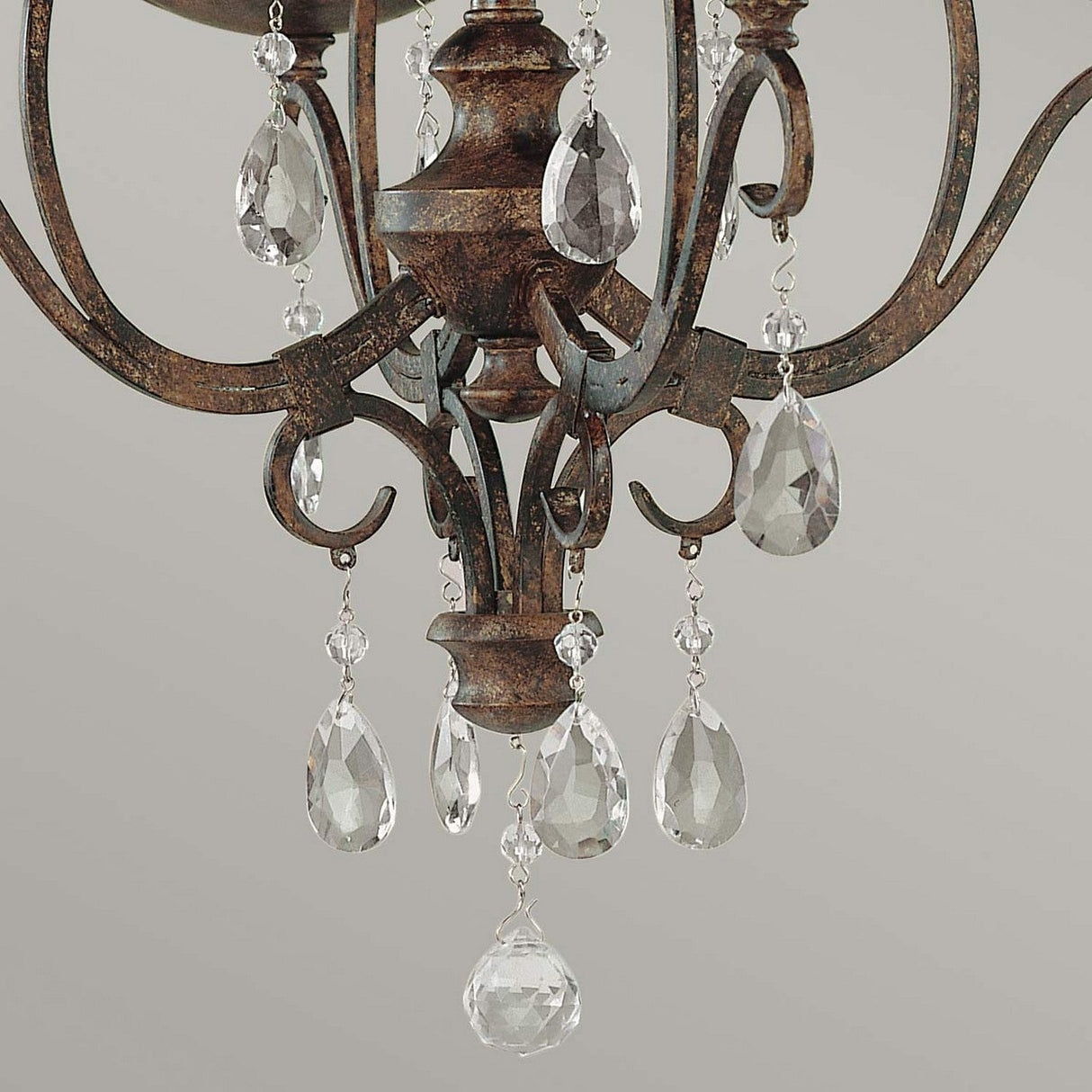 Close-up of the Chateau 4 Light Chandelier in mocha bronze with crystal accents. The swirling metal arms and hanging crystal teardrop pendants enhance its elegant and classic appearance.