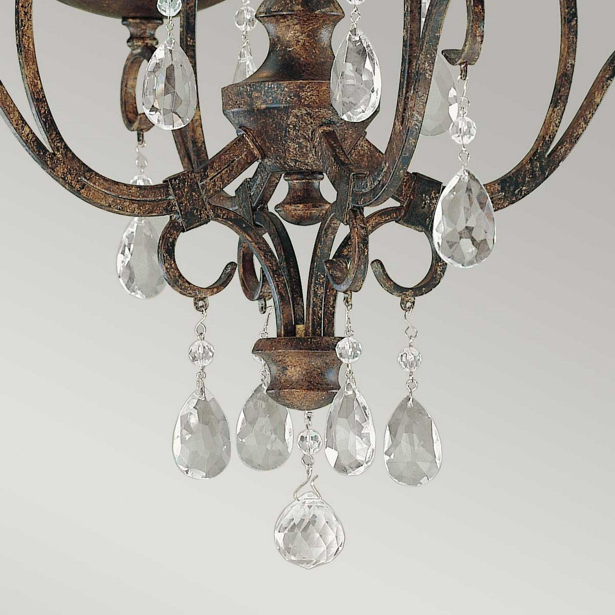 Close-up of the Chateau 4 Light Chandelier in a mocha bronze finish, featuring intricate metalwork and an array of dangling, teardrop-shaped crystal accents that capture light beautifully, creating a sparkling effect against a neutral background.