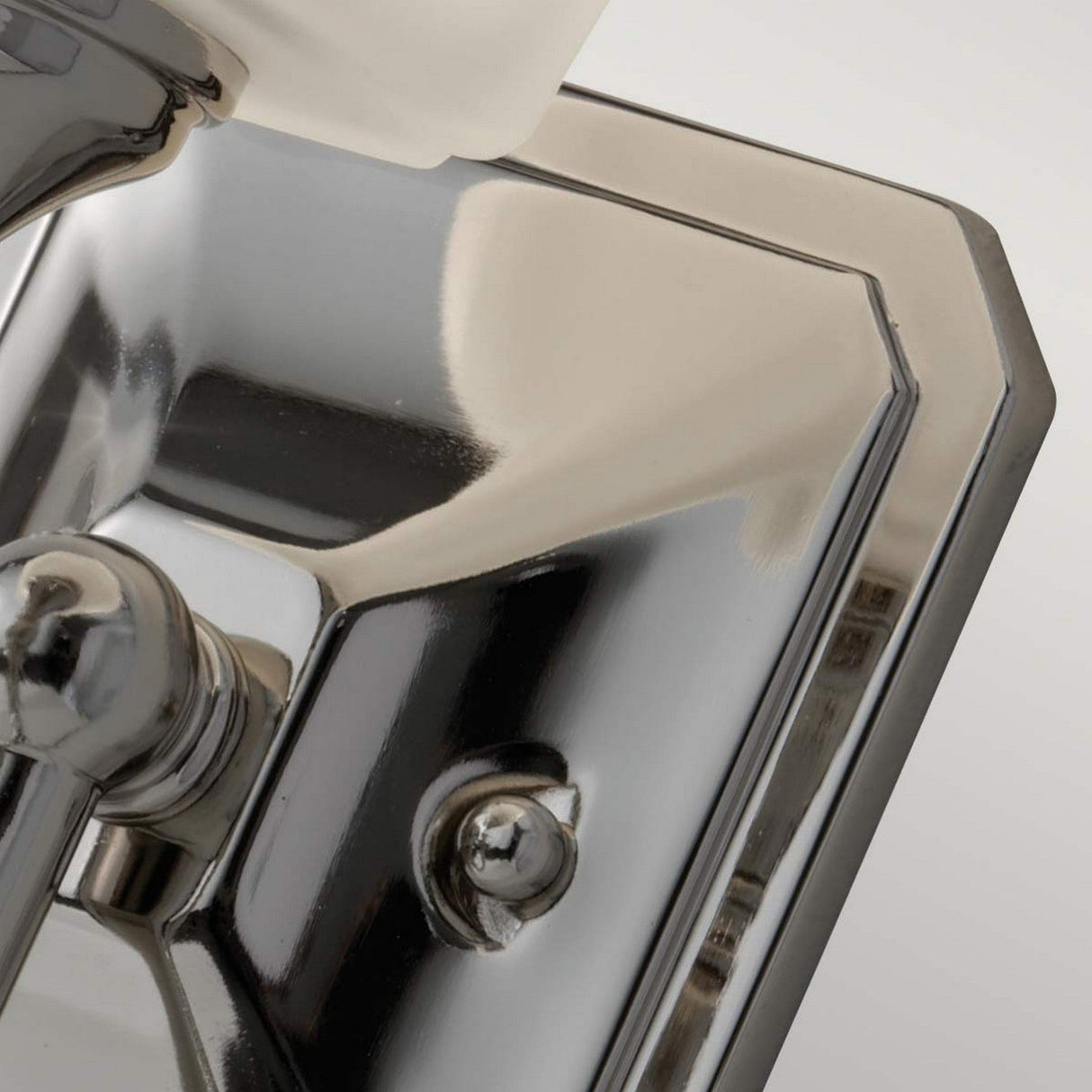 A close-up of the Concord 1 Light Wall Light - Polished Chrome showcases its polished chrome finish with an opal-etched glass shade partially visible, highlighting its role as part of a light fixture that elegantly reflects light and shadows on its sleek surface.