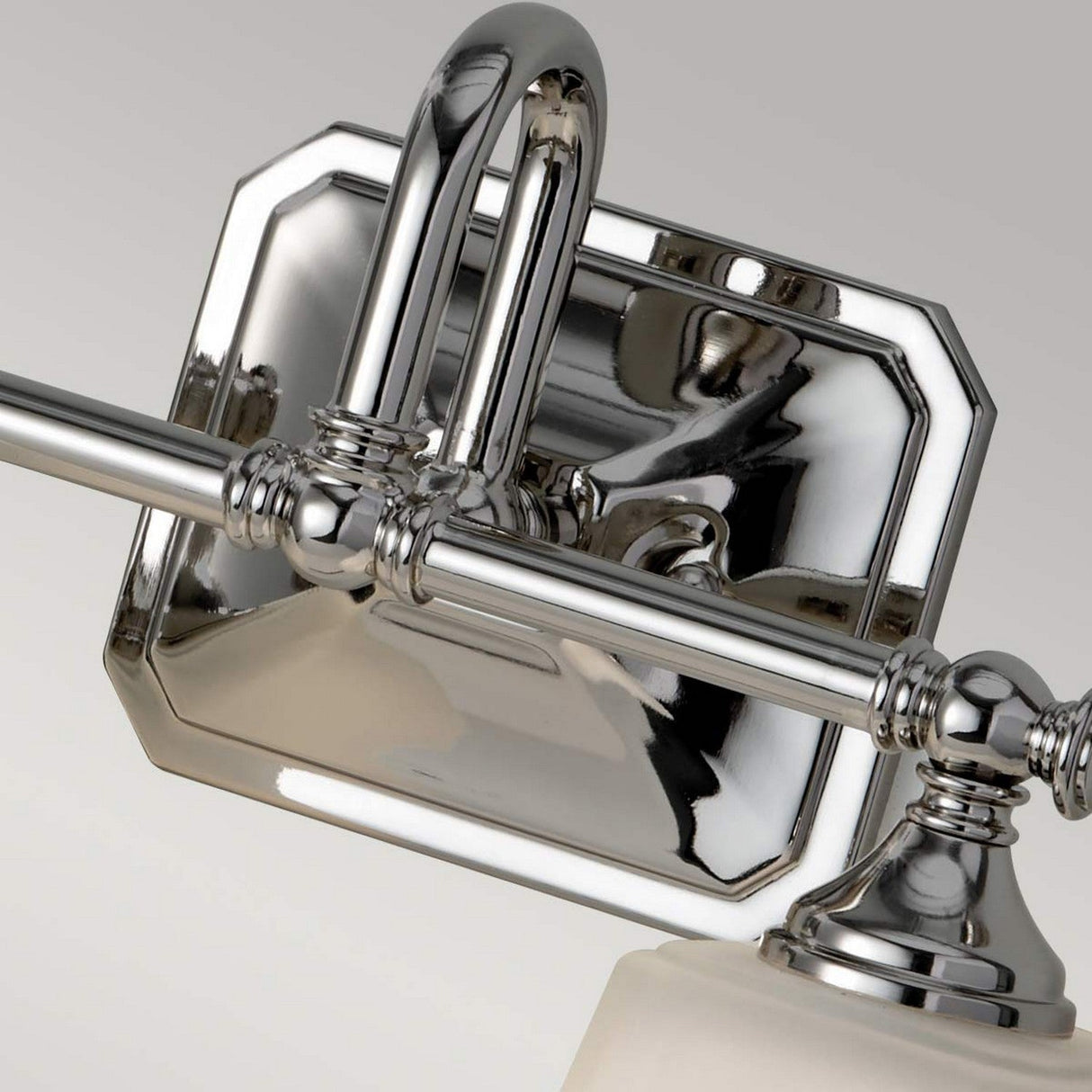 A close-up view showcases the polished chrome Concord 2 Light Wall Light, which boasts a decorative rectangular base and intricate detailing. This fixture features a sleek, modern design highlighted by opal-etched glass shades, set against a light gray backdrop.