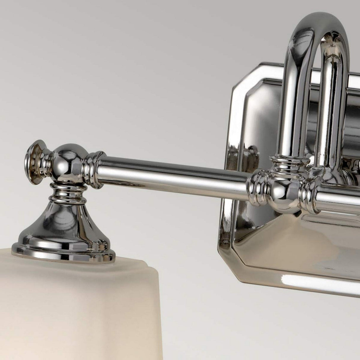 A detailed view of the Concord 2 Light Wall Light - Polished Chrome reveals an elegant metallic wall-mounted fixture featuring opal-etched glass shades. It is mounted on a rectangular chrome backplate, highlighting a fusion of modern and classic design elements.