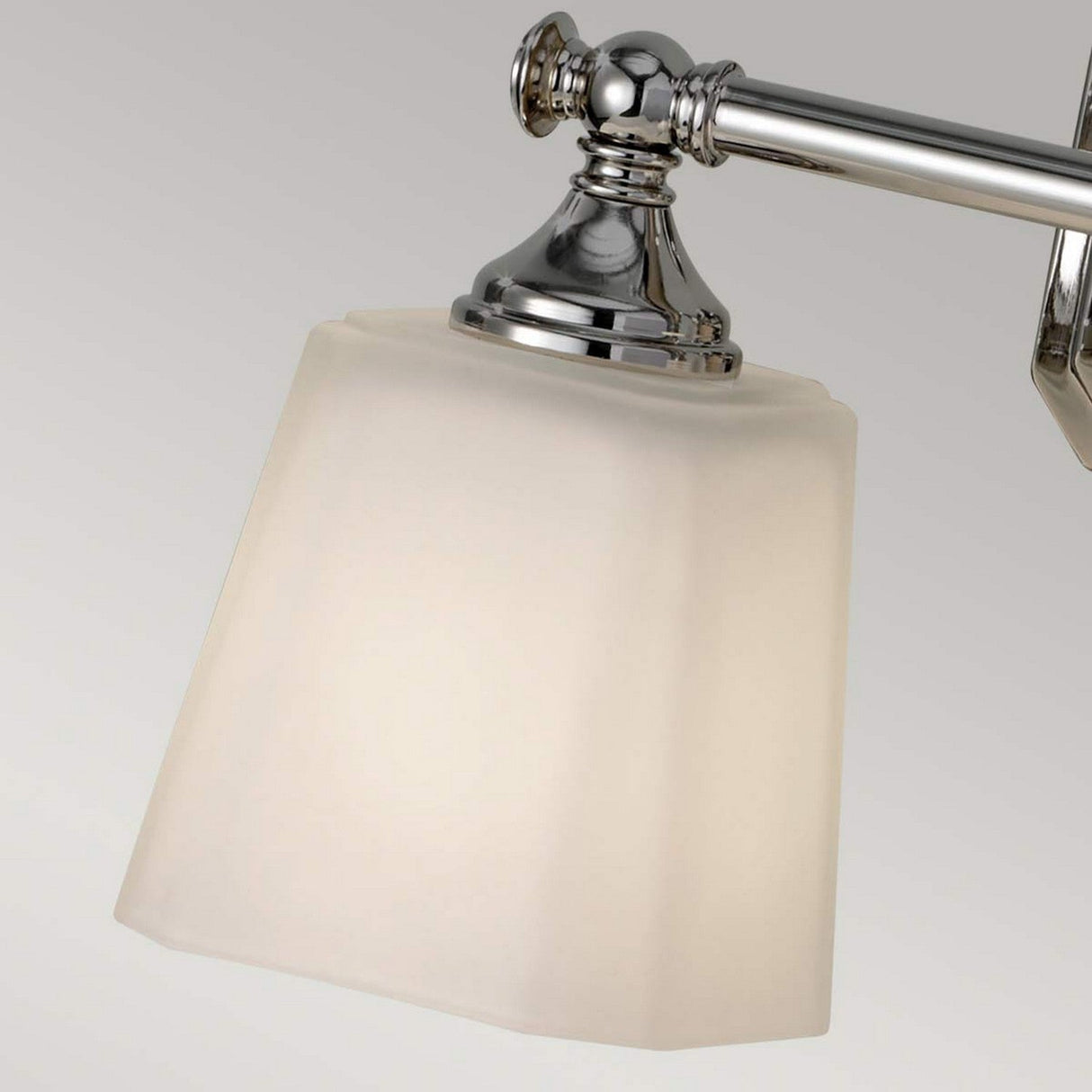 A detailed view of the Concord 2 Light Wall Light - Polished Chrome showcases a sleek chrome fixture with a metallic arm and base. It includes opal-etched glass shades that disperse soft, white light against a neutral gray background.