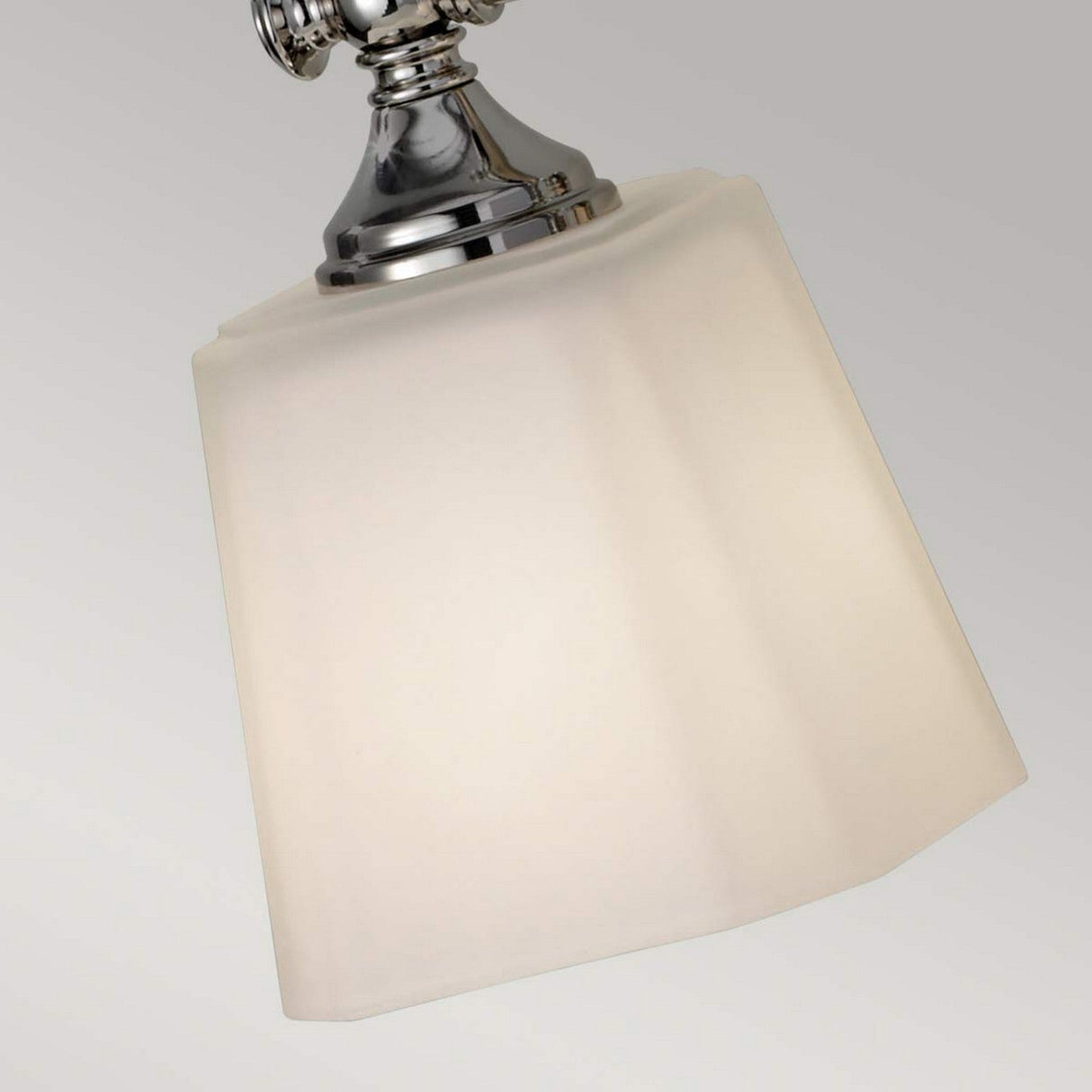 Close-up of a ceiling light fixture featuring a polished chrome base and a frosted, angled square lampshade. The simple light gray background emphasizes the fixture's sleek and modern design, similar to the Concord 3 Light Wall Light - Polished Chrome.