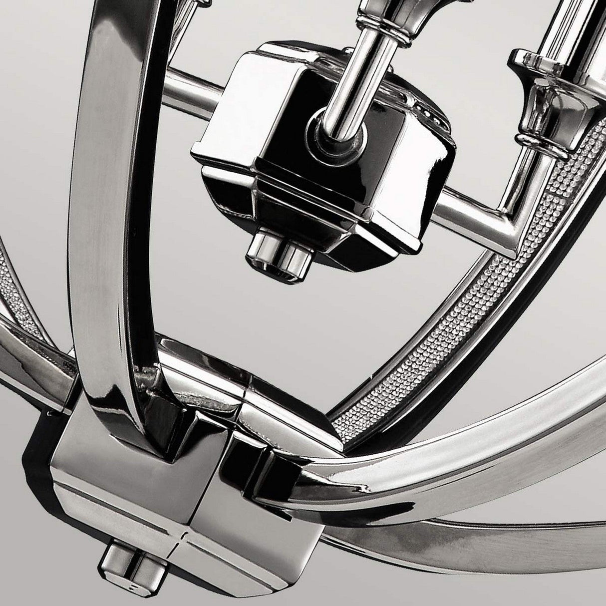 Close-up of the Corinne 3 Light Medium Chandelier in polished nickel, highlighting its minimalist elegance with sleek arcs and geometric components. The design showcases reflective surfaces and intricate detailing, set against a neutral background.