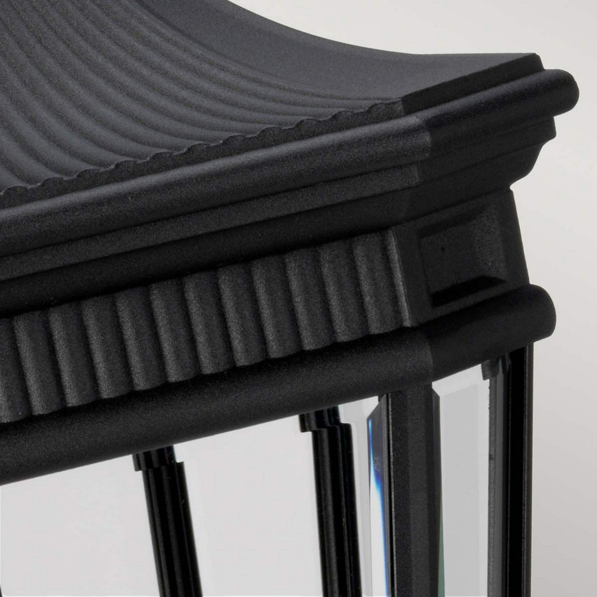 Close-up of the Cotswold Lane 3 Light Outdoor Large Pedestal in black, featuring a ribbed, curved top with vertical clear glass panels. This lighting piece adds a classic and elegant touch with its intricate frame detailing.