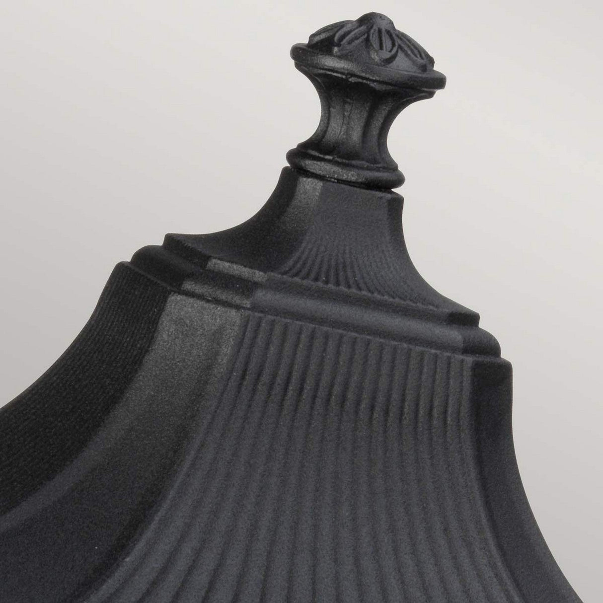 Close-up of the Cotswold Lane 2 Light Outdoor Medium Light in black, featuring ornate detailing and vertical grooves reminiscent of antique gas lanterns, set against a plain gray background.