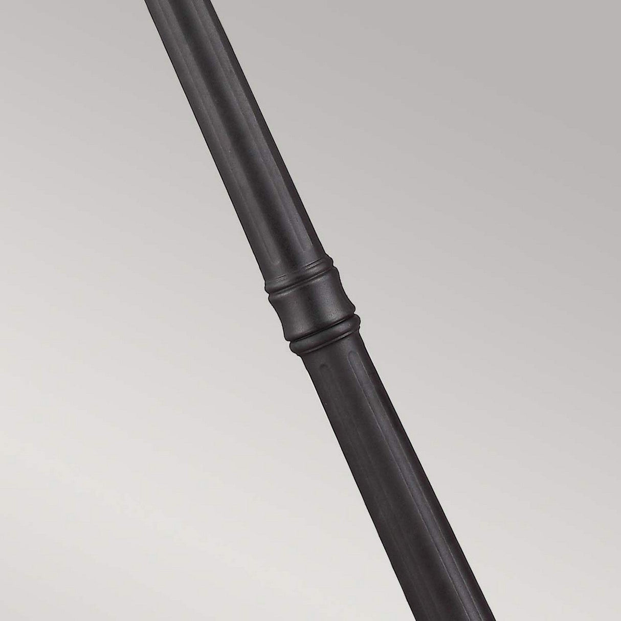 A close-up of the Cotswold Lane 3 Light Large Post in black, showcasing its smooth, cylindrical surface with a wider band around the middle, reminiscent of elegant outdoor lighting, set against a light gray background.