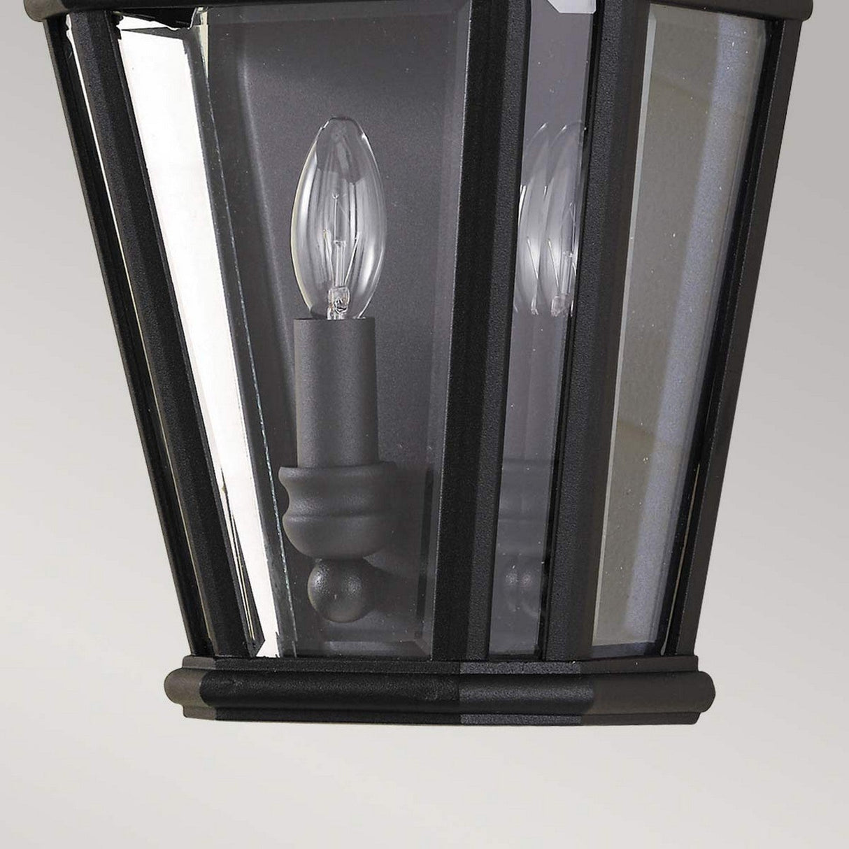 Close-up of the Cotswold Lane 2 Light Outdoor Wall Lantern in a black finish, showcasing its clear beveled glass panels and housing candle-shaped bulbs inside.